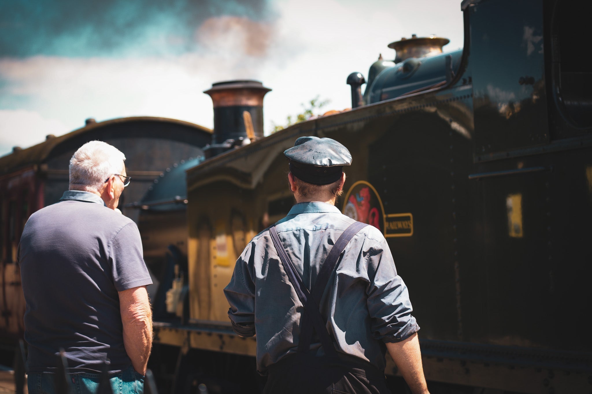 Heritage railway volunteers at the East Somerset Railway watching a steam locomotive at Cranmore station